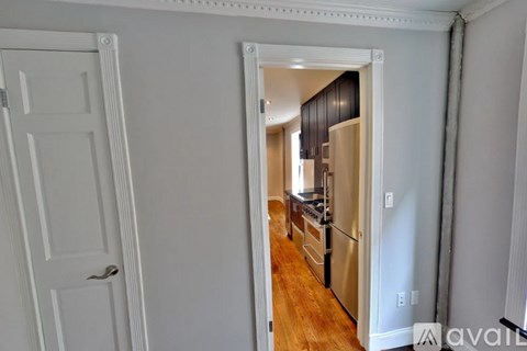 A kitchen with a stainless steel refrigerator and wooden floors.