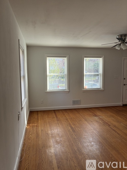 A room with wooden floors and two windows.