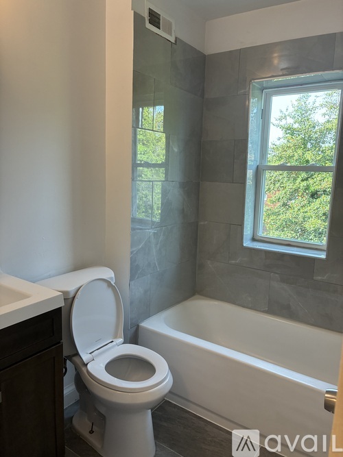 A bathroom with a toilet, tub, and window.