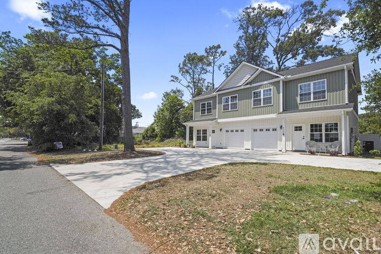 A house with a grey roof and white garage doors is surrounded by trees.