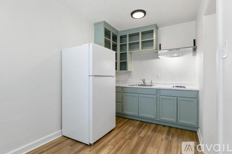 A kitchen with a white refrigerator and blue cabinets.