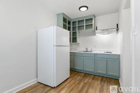 A kitchen with a white refrigerator and blue cabinets.