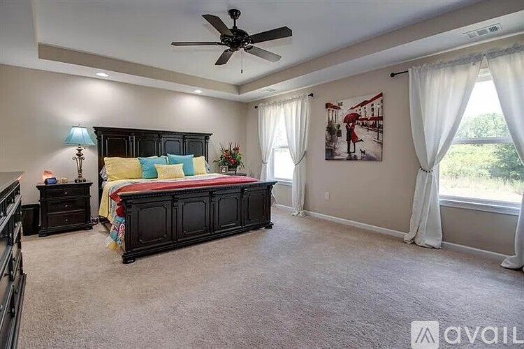 A bedroom with a large bed and a ceiling fan.