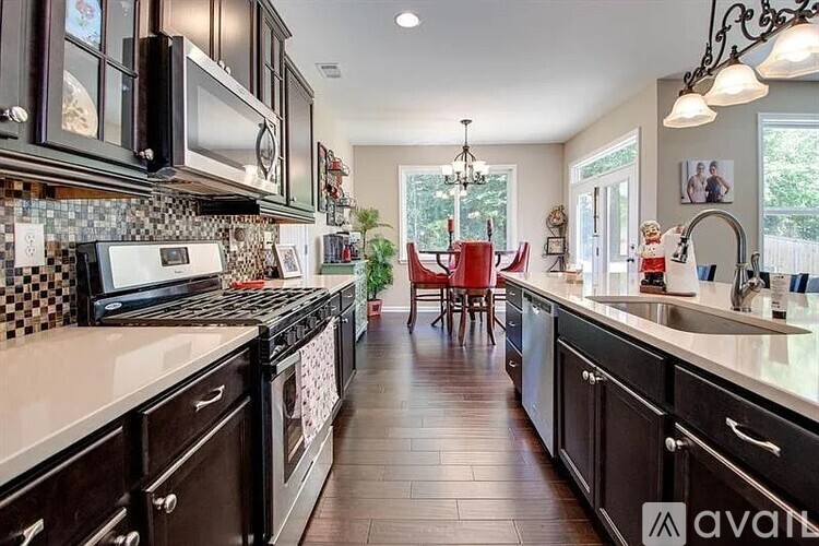 A kitchen with black cabinets and a checkered backsplash.