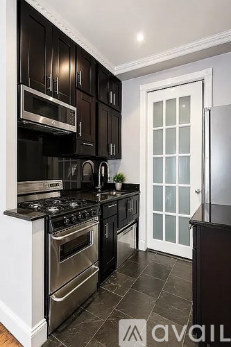 A kitchen with black cabinets and a white door.
