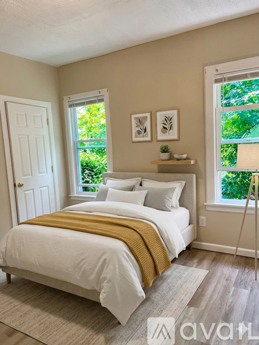 A bedroom with a white bed and a yellow throw blanket.