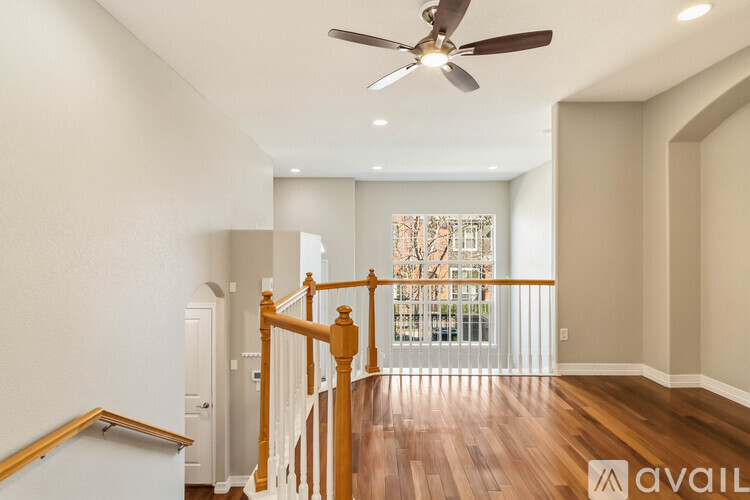 A spacious room with a ceiling fan and a staircase leading to the second floor.