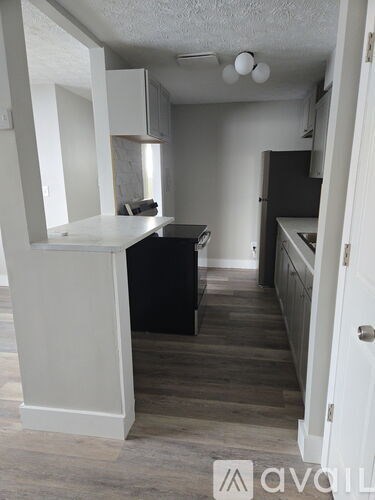 A kitchen with white cabinets and a black counter.