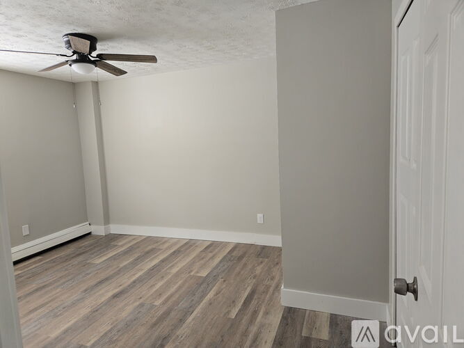 A room with a ceiling fan and wooden flooring.