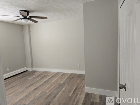A room with a ceiling fan and wooden flooring.