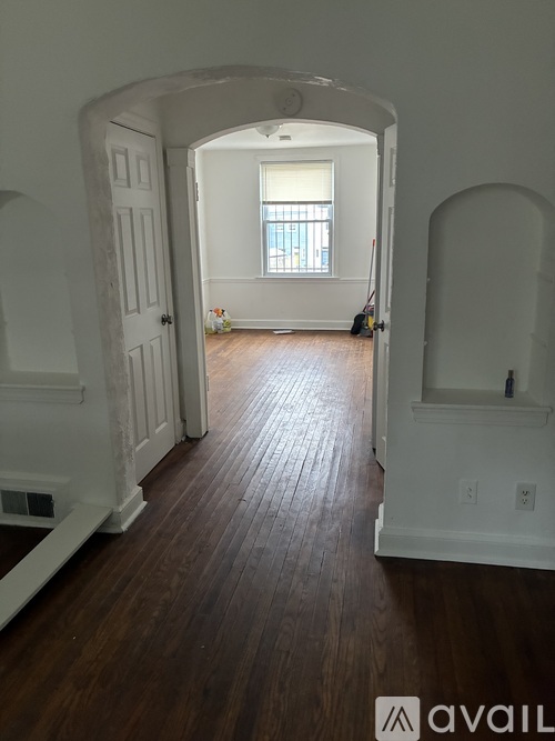A hallway with wood floors and white walls.