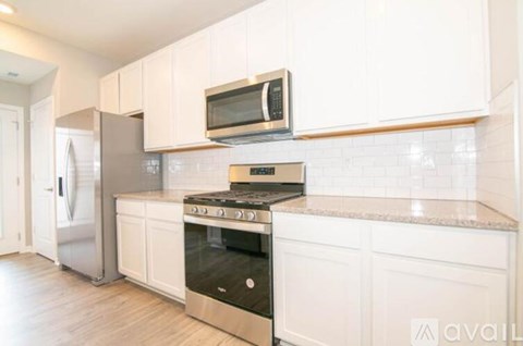 A kitchen with white cabinets and a stainless steel refrigerator.