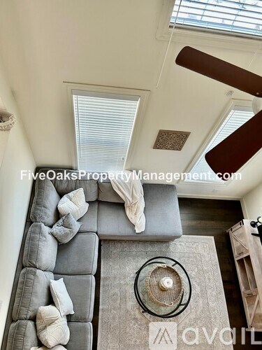 A living room with a grey couch and a wooden staircase.