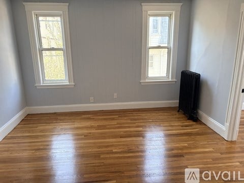 A room with wooden floors and two windows.