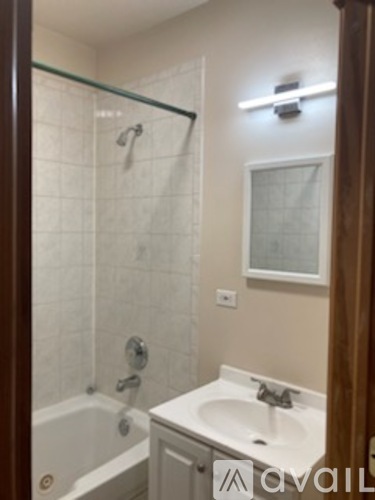 A bathroom with a white sink and a glass shower door.