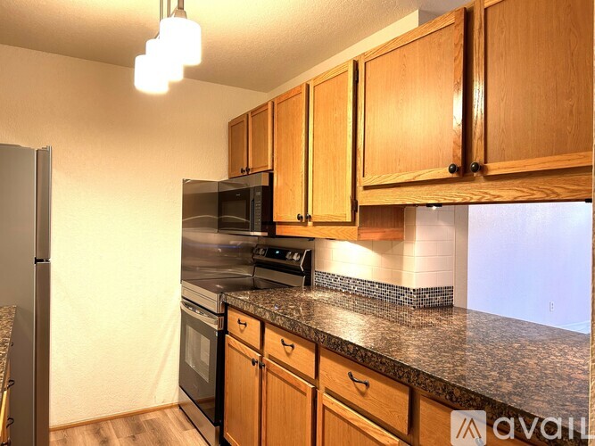 A kitchen with wooden cabinets and granite countertops.