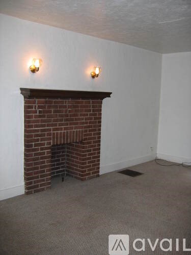A room with a brick fireplace and two lights on the wall.