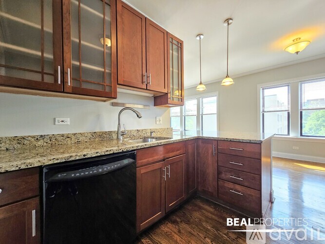 A kitchen with dark wood cabinets and a black dishwasher.