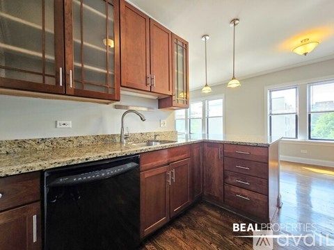 A kitchen with dark wood cabinets and a black dishwasher.
