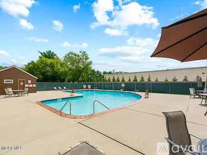 A pool with a brown umbrella and chairs around it.