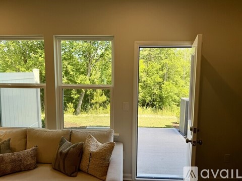 A living room with a couch and a large window overlooking a green outdoor area.