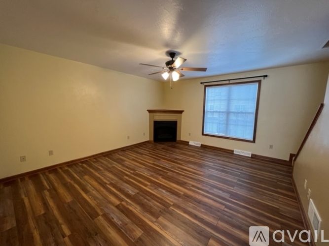 A spacious room with wooden flooring and a ceiling fan.