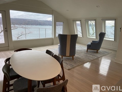 A living room with a large table and chairs and a view of a lake through the windows.