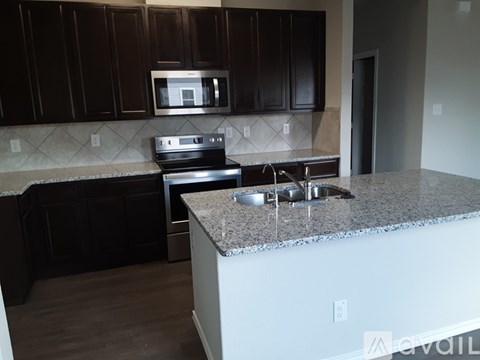 A kitchen with a granite countertop and dark brown cabinets.