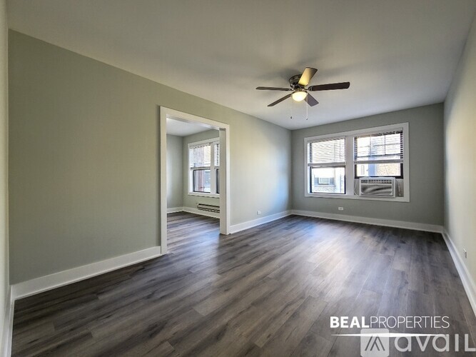 A spacious room with a ceiling fan and two windows.