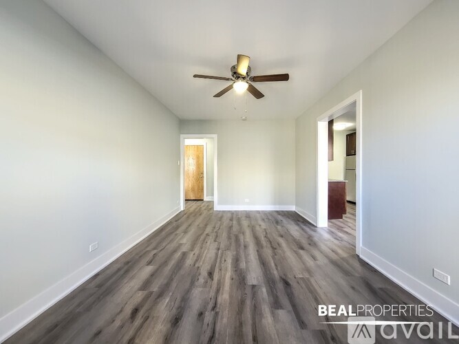 A spacious room with a ceiling fan and wooden flooring.