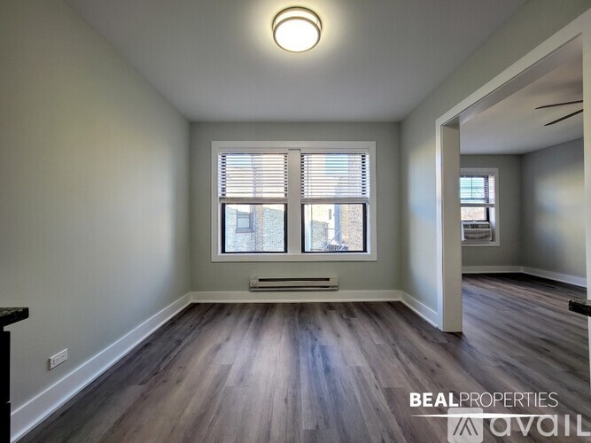A room with wooden floors and a window with blinds.