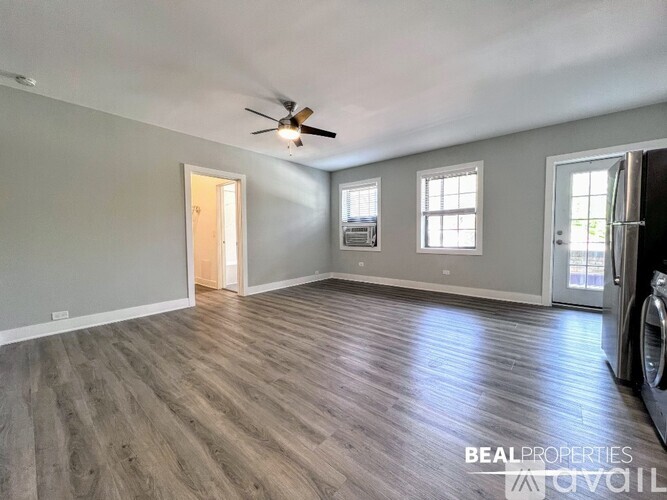 A spacious room with a ceiling fan and hardwood flooring.