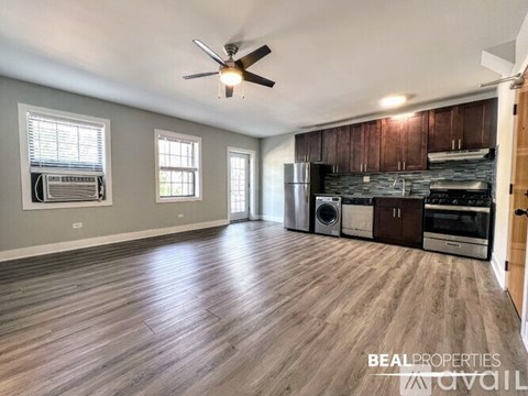A spacious kitchen and living room with wood flooring and a ceiling fan.