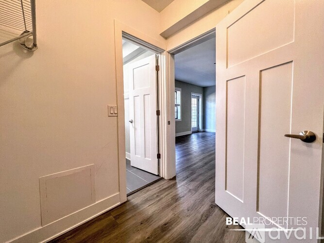 A hallway with a white door and a white wall.