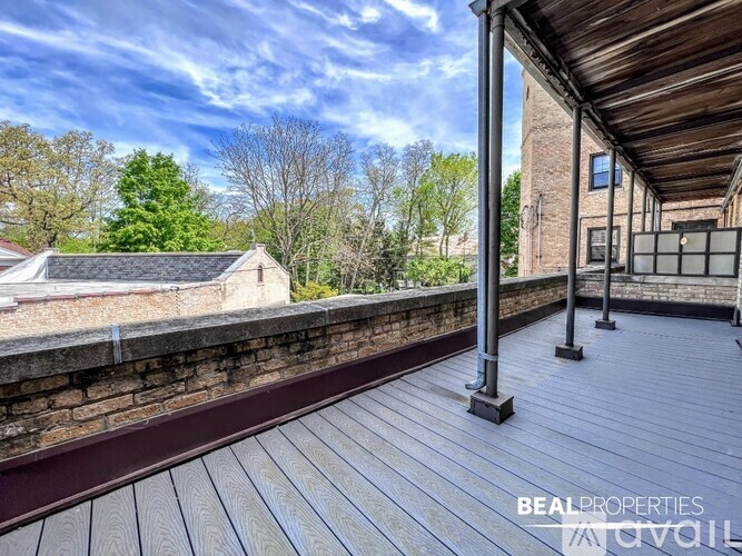 A wooden deck with a railing and a building in the background.
