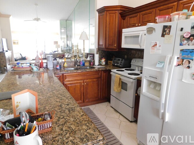 A kitchen with a granite countertop and a refrigerator covered in magnets.