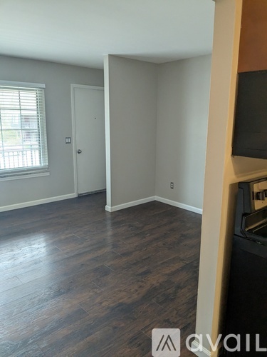 A room with wood flooring and a window with blinds.