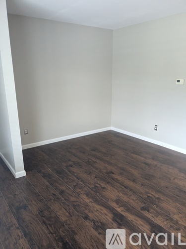 A room with wooden flooring and a white wall.