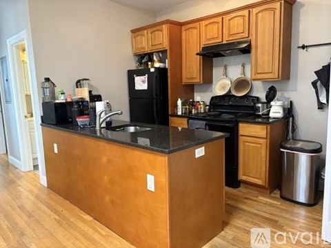 A kitchen with wooden cabinets and a black fridge.