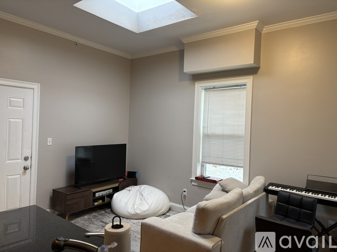 A living room with a television, a chair, a couch, and a piano.