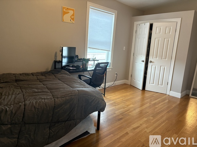 A bedroom with a bed, chair, and a window.
