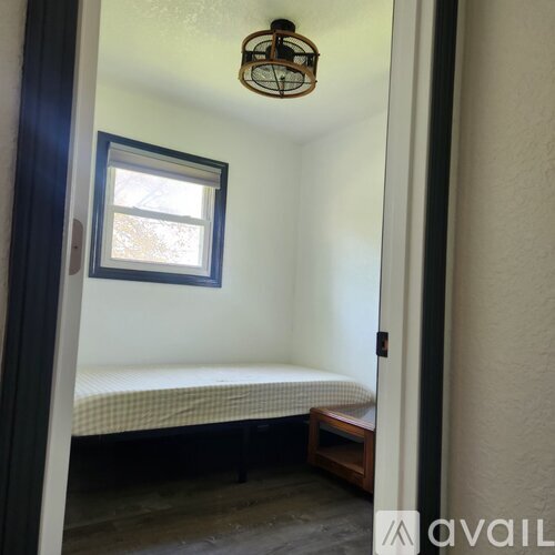 A small bedroom with a bed and a window.
