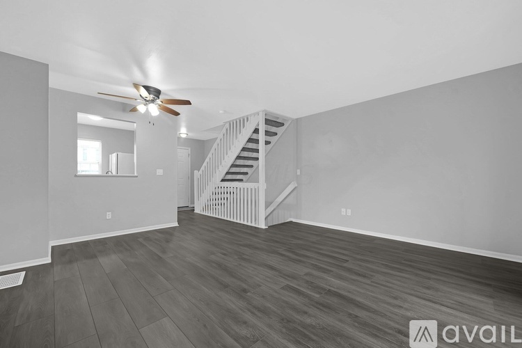 A spacious room with a staircase and a ceiling fan.