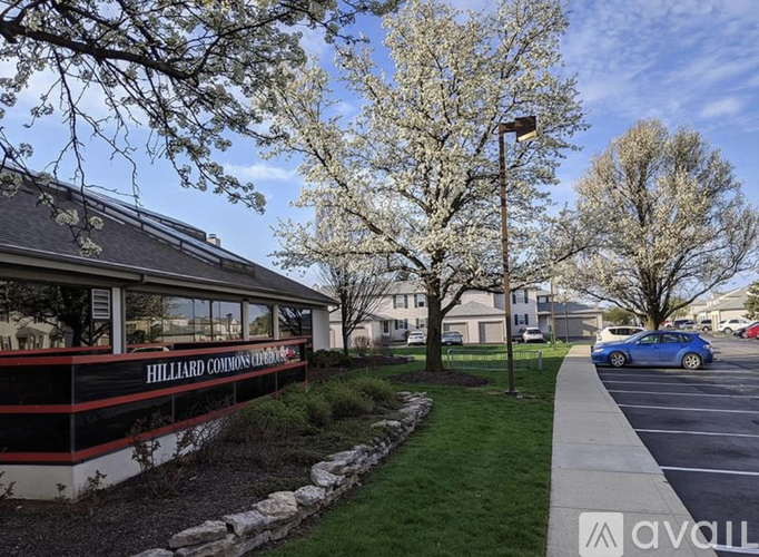 A car is parked in a parking lot in front of a building with the sign "Hilliard Commons".