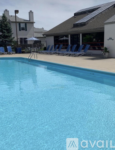 A pool with chairs around it and a house in the background.