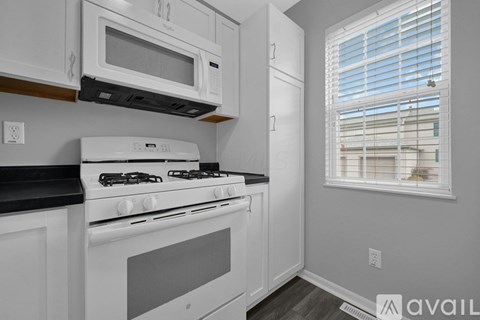 A kitchen with white cabinets and a black countertop.