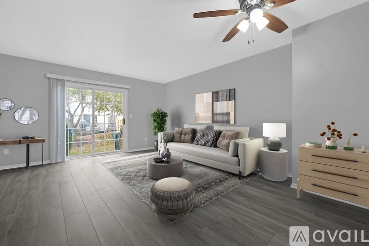A modern living room with a grey sofa, a wooden coffee table, and a ceiling fan.