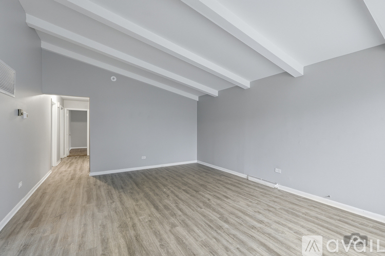 A spacious room with wooden flooring and white walls.