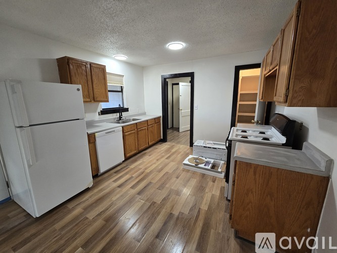 A kitchen with white appliances and wooden cabinets.