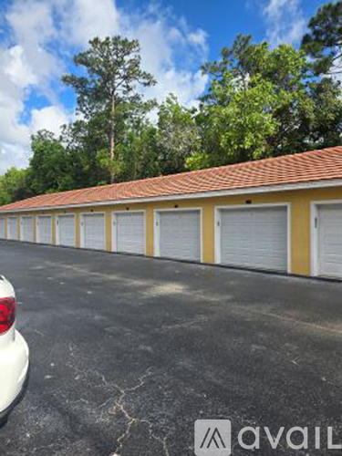A white car is parked in front of a yellow building with a red roof.